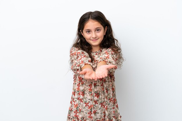 Mała kaukaska dziewczynka na białym tle trzymająca wyimaginowaną copyspace na dłoni, aby wstawić reklamę