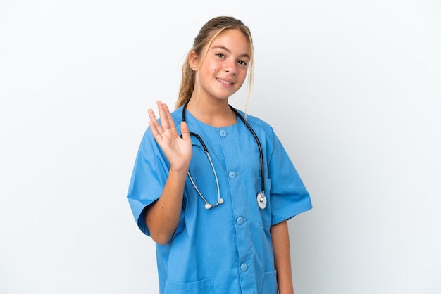 Mała kaukaska dziewczynka przebrana za chirurga na białym tle salutująca ręką ze szczęśliwym wyrazem twarzy