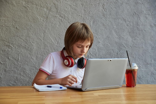mała kaukaska uczennica siedzi na zewnątrz na klawiaturze laptopa