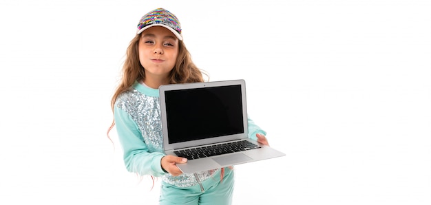 Mała ładna caucasian dziewczyna w dresie trzyma nowego laptop, panorama odizolowywająca na biel ścianie