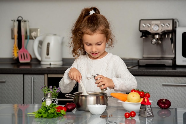 Mała ładna dziewczyna gotuje w kuchni ze świeżych warzyw. Fotografia konceptualna. Odpowiednie odżywianie. Dieta.