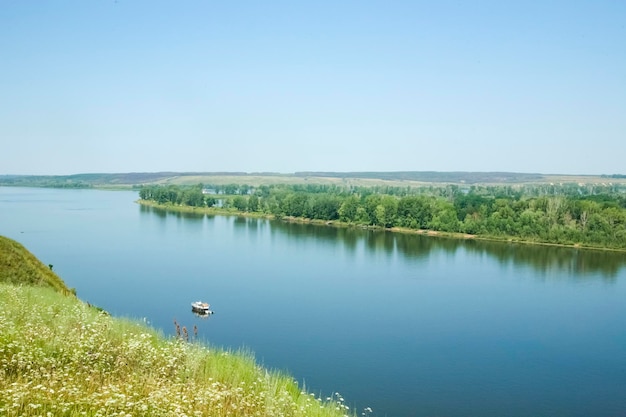 Mała łódka na niebieskiej rzece i zielonym brzegu