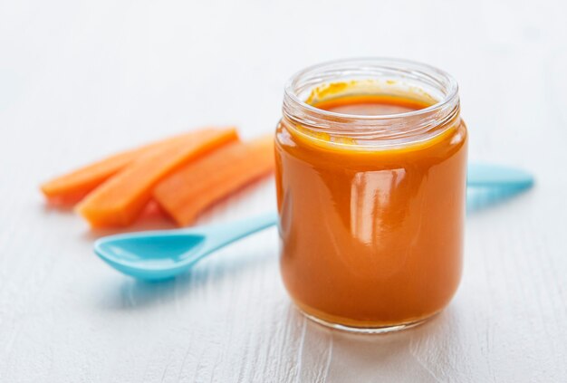 Mała marchewka tłuczona łyżką w szklanym słoju, jedzenie dla dzieci