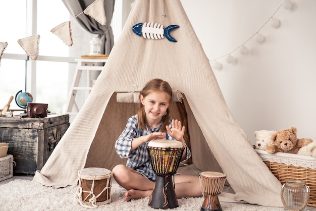 Mała Perkusistka Grająca Na Djembe, Siedząca Przed Etnicznym Namiotem W Domu