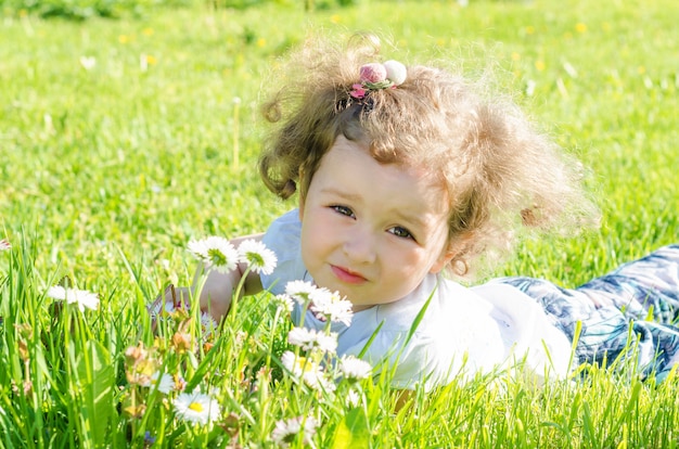 Mała piękna dziewczyna w polu z stokrotkami. wesoły dziecko z kwiatami w przyrodzie.