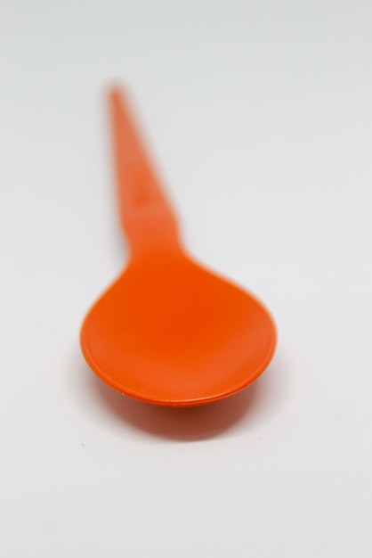 Zdjęcie mała pomarańczowa łyżeczka z długą rączką i długą rączką.