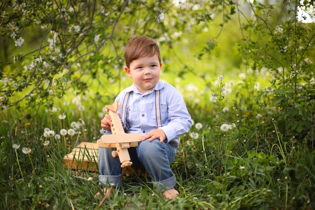 Mała śliczna Blond Chłopiec Bawić Się Z Drewnianym Samolotem W Lato Parku Na Trawie Na Słonecznym Dniu