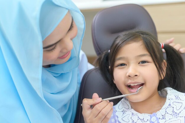 Mała śliczna dziewczyna o zębach zbadanych przez muzułmańskiego dentystę w klinice dentystycznej zęby sprawdzanie i koncepcja zdrowych zębów