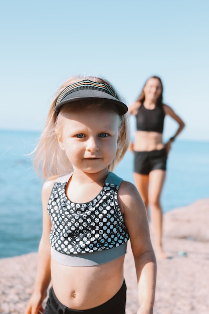 Mała śliczna dziewczyna patrzeje kamerę na tle dysponowana mama na plaży