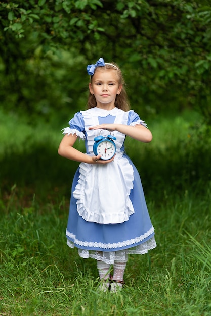Mała śliczna Dziewczyna W Kostiumu Alice Trzyma Starego Antykwarskiego Zegar.