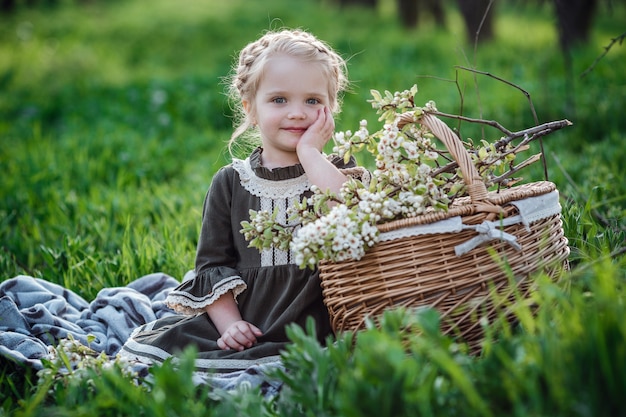 Mała śliczna Dziewczyna W Sukience W Ogrodzie Kwiat. Cute Dziewczynka 3-4 Lat Gospodarstwa Kwiaty Nad Naturą. Portret Wiosny. Aromatyczny Kwiat I Koncepcja Retro Vintage.