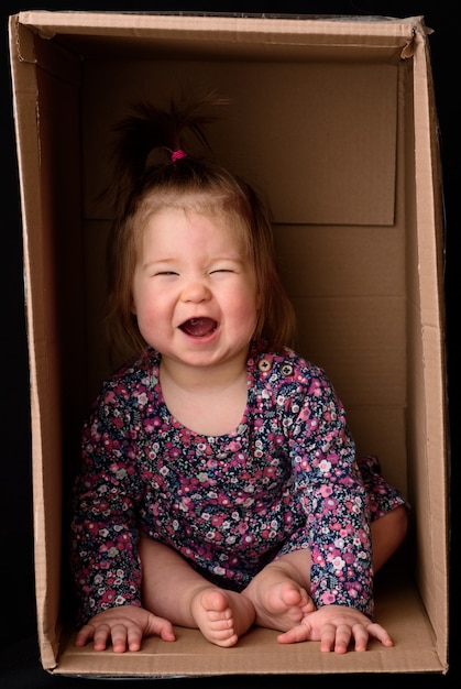 Mała śliczna, piękna dziewczyna siedzi w pudełku.