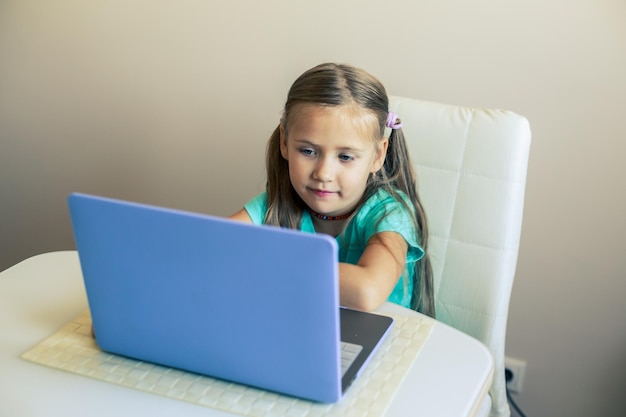 Zdjęcie mała słodka dziewczynka używa laptopa do prowadzenia wideorozmowy