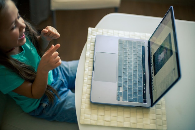 Mała słodka dziewczynka używa laptopa do prowadzenia wideorozmowy