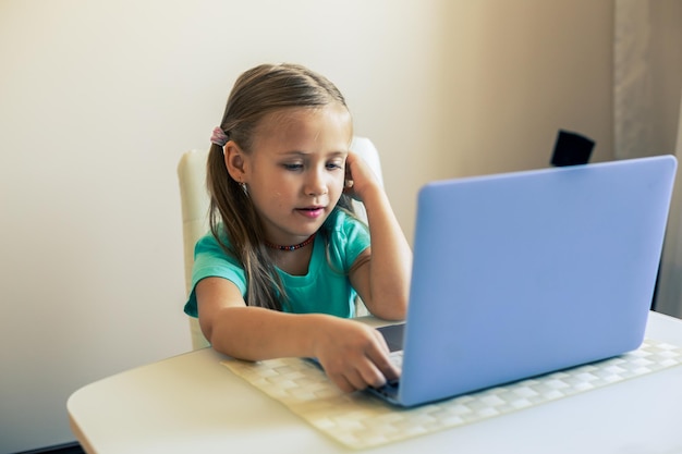 Zdjęcie mała słodka dziewczynka używa laptopa do prowadzenia wideorozmowy