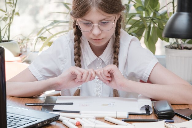 Zdjęcie mała studencka dziewczyna studiuje w szkole. domowe hobby. uśmiechnięta dziecko dziewczyna obraz w domu. kształcić się przez nauczyciela vs uczyć się i uczyć w domu z rodzicami. młoda dziewczyna odrabianiu lekcji.