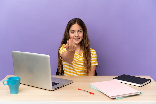 Mała studentka w miejscu pracy z laptopem na białym tle na fioletowym tle zapraszając do przyjścia z ręką. Cieszę się, że przyszedłeś