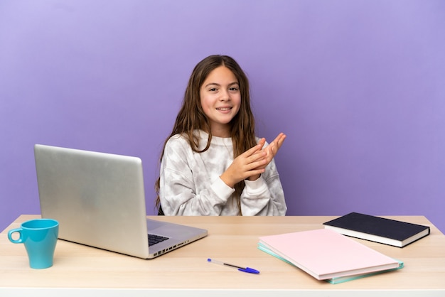 Mała studentka w miejscu pracy z laptopem odizolowanym na fioletowej ścianie brawo po prezentacji na konferencji