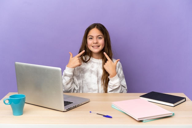 Mała studentka w miejscu pracy z laptopem odizolowanym na fioletowej ścianie dająca gest kciuka w górę