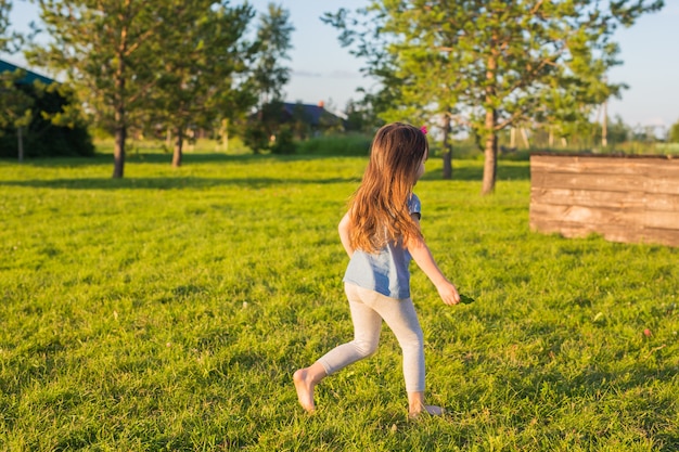 Mała szczęśliwa dziewczynka bawi się w letnim parku
