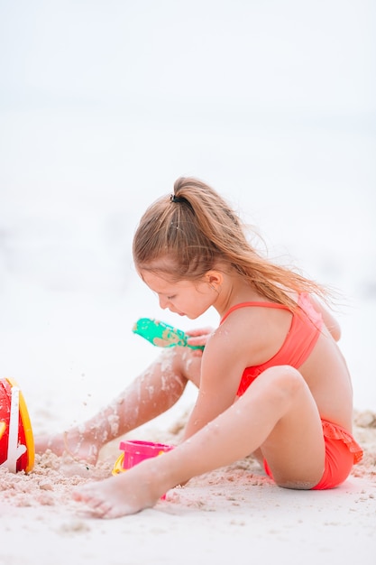 Mała urocza dziewczyna bawić się na plaży z piłką