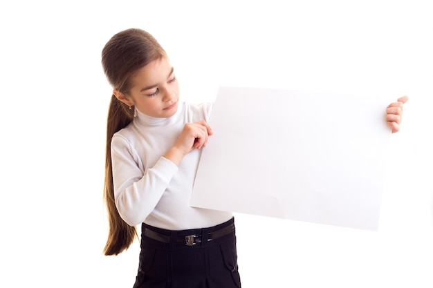 Mała uśmiechnięta dziewczynka z długim brązowym kucykiem w białej koszuli i czarnej spódnicy, trzymająca biały sztandar