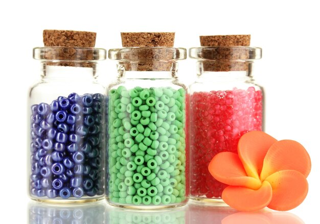 Zdjęcie małe butelki pełne kolorowych koralików wyizolowanych na białym