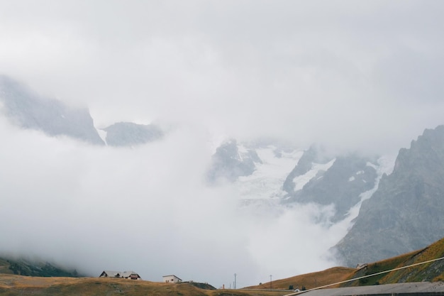 Małe domy na tle ogromnego lodowca w górach jesienny krajobraz we francuskich alpach