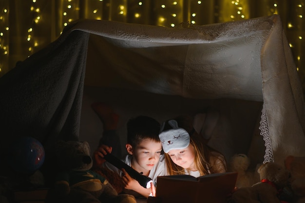 Małe dzieci czytające bajkę na dobranoc w domu