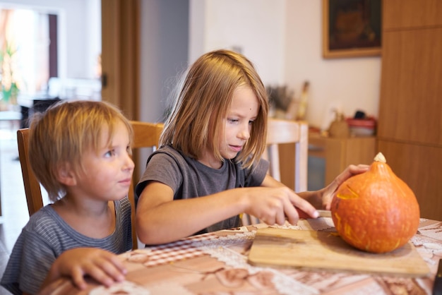 Małe dzieci rzeźbią dynię na Halloween