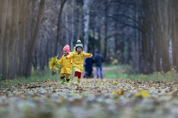 Małe dzieci spacerują po jesiennym parku jesienią liści