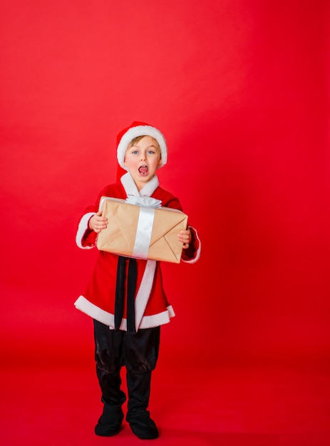 Małe dziecko chłopiec przebrany za Świętego Mikołaja. Świąteczne zakupy. Prezent gwiazdkowy. Dzieciństwo