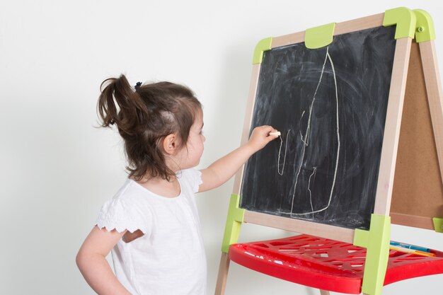 Małe dziecko dziewczyna robi kredowemu rysunkowi