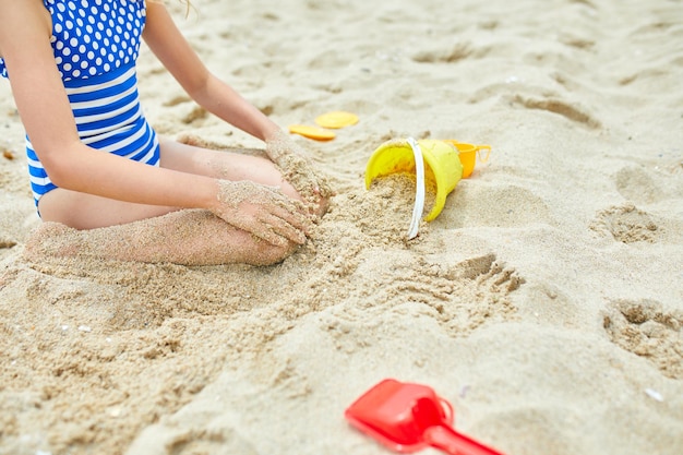 Małe dziecko dziewczynka bawi się na plaży i bawi się piaskiem zabawki rodzinne letnie wakacje Tło z pustym miejscem na tekst