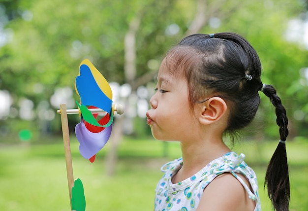 Małe dziecko dziewczyny dmuchanie silnik wiatrowy w ogródzie