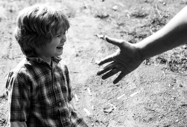 Zdjęcie małe dziecko płacze w parku ojcowie wspierają syna ręką, która pomaga koncepcja koncepcji ojcostwa
