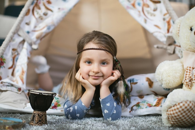 Małe dziecko płci żeńskiej leżące wewnątrz wigwamu w domu