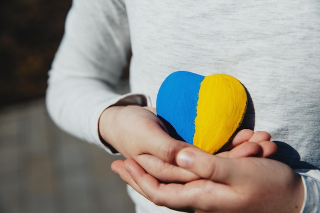 Małe dziecko trzyma kamień w kształcie serca z flagą narodową Ukrainy lub hymnem