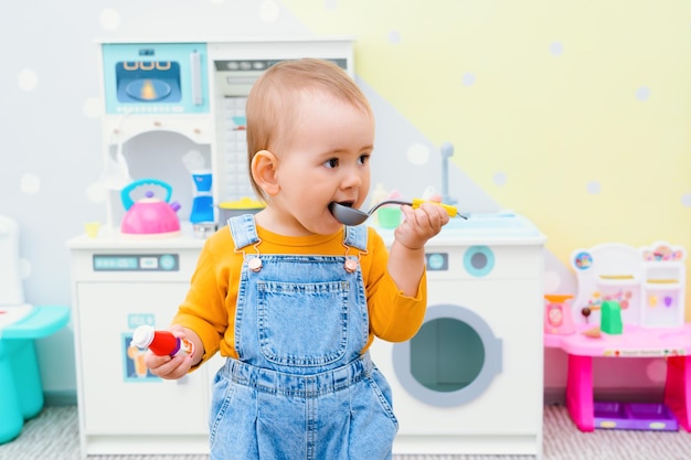 Małe Dziecko Trzyma W Rękach Chochlę W Dziecięcej Kuchni Zabaw