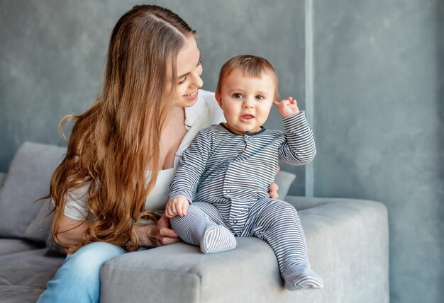 Małe dziecko uśmiechnięte i szczęśliwe z mamą na kanapie