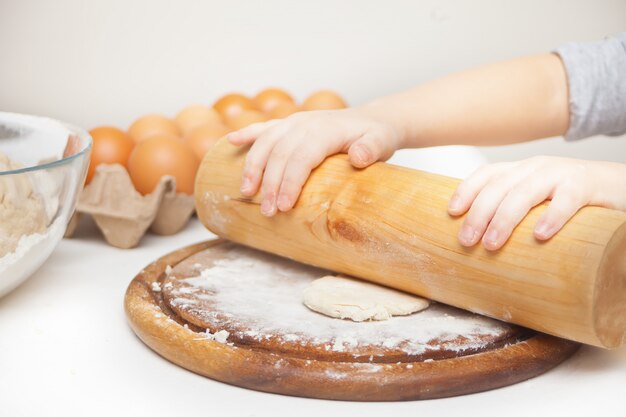 Zdjęcie małe dziecko w domowej kuchni przygotowujące ciasto na pizzę lub inne jedzenie.