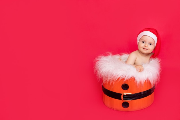 Małe dziecko w kapeluszu Santa siedzi w wiadrze