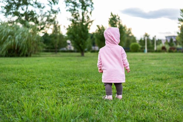 Małe dziecko w różowej bluzie studiuje otaczający go świat, przyrodę, łączenie z naturą, spacery w plenerze