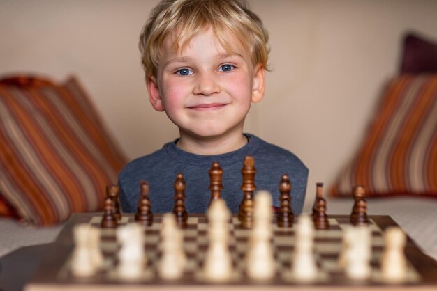 Małe dziecko w wieku 5 lat gra w szachy na dużej szachownicy Szachownica na stole przed chłopcem myślącym o następnym ruchu