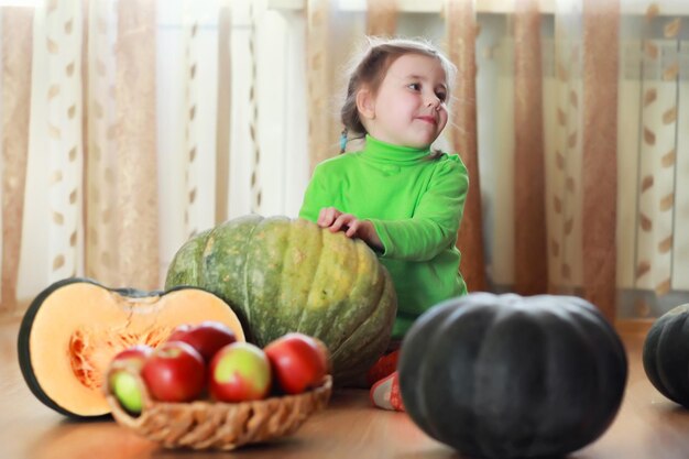 Małe dziecko wybiera dynię jesienią. Dziecko siedzi na gigantycznej dyni. Dynia to tradycyjne warzywo używane w amerykańskie święta - Halloween i Święto Dziękczynienia.