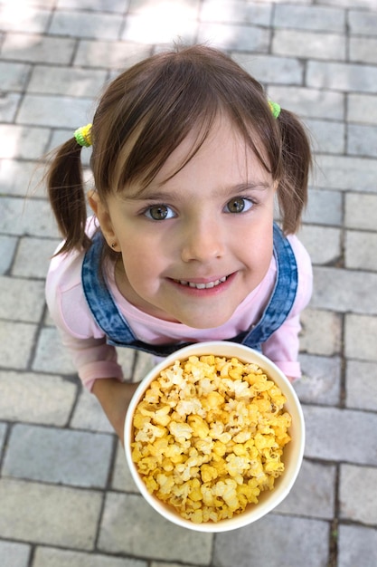 Małe dziecko z wiadrem popcornu uśmiecha się i podnosi wzrok