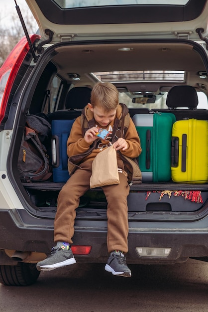Małe dziecko zaglądające do papierowej torby z cukierkami w bagażniku samochodu