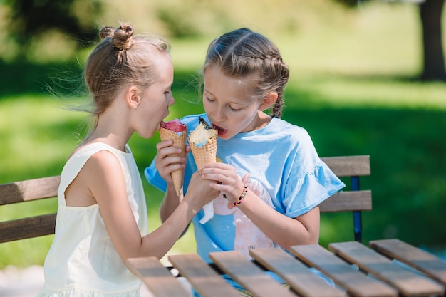 Małe Dziewczynki Je Lody Outdoors Przy Latem W Plenerowej Kawiarni