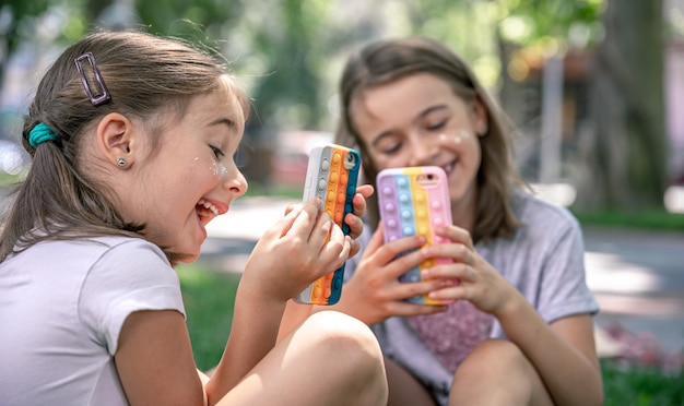 Małe Dziewczynki Na Zewnątrz Z Telefonami W Etui Z Pryszczami, Modna Zabawka Antystresowa.