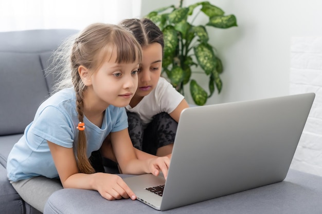 Zdjęcie małe dziewczynki w domu z laptopem, rozmowy wideo z przyjaciółmi.